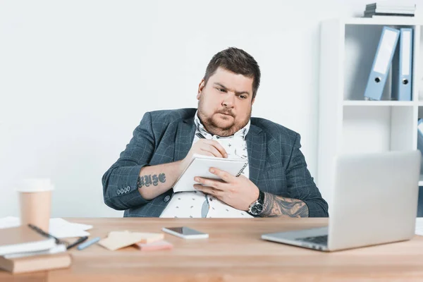Übergewichtiger Geschäftsmann Anzug Schreibt Notizblock Und Arbeitet Arbeitsplatz Mit Laptop — Stockfoto