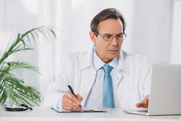 doctor sitting at table and working with laptop