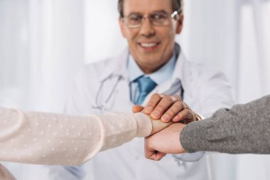 Doktor ve iki hasta el ele tutuşarak kırpılmış görüntü