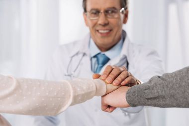 cropped image of doctor and two patients holding hands clipart