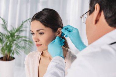 Doktor kadın hasta kulak inceleyerek görüntü kırpılmış