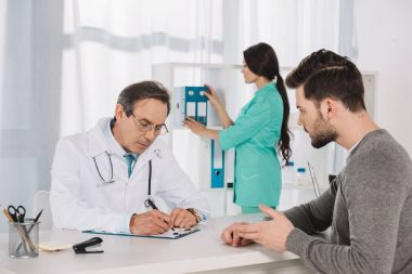 male patient talking to doctor at clinic clipart