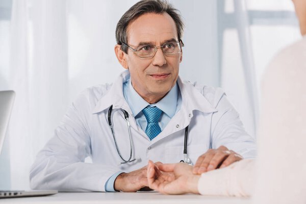 cropped image of doctor measuring patient pulse