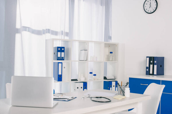 ноутбук и стетоскоп за рабочим столом в клинике
