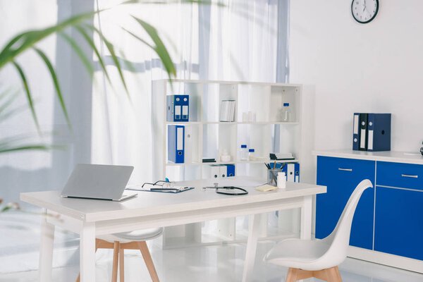 стол со стульями и полками с документами на рабочем месте в больнице
