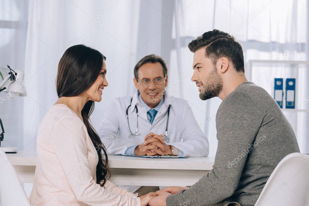 happy couple holding hands at clinic and looking at each other