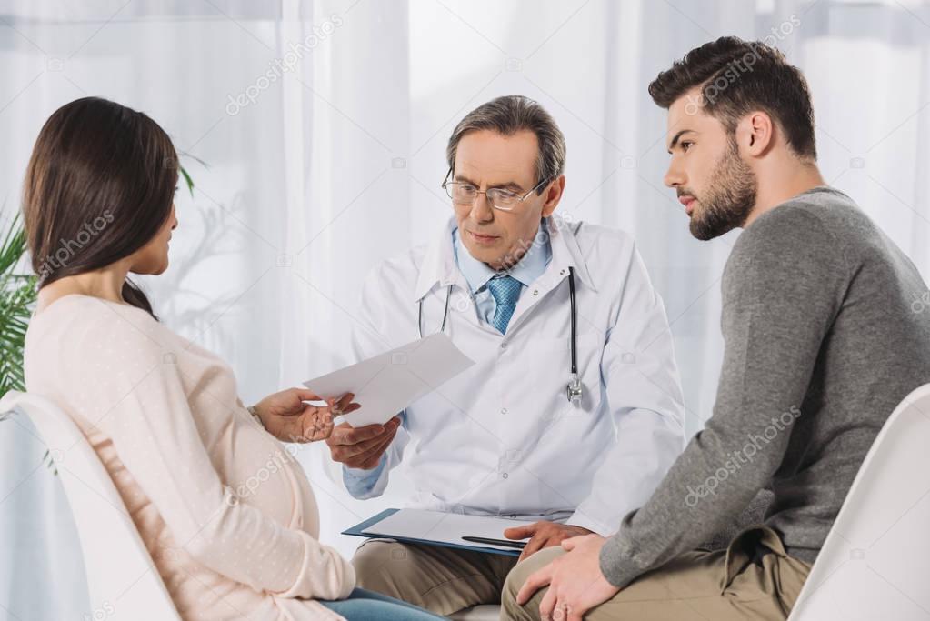 doctor giving documents to couple expecting child