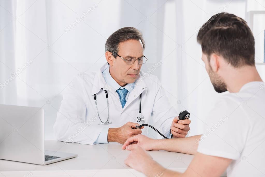 doctor measuring male patient pressure 