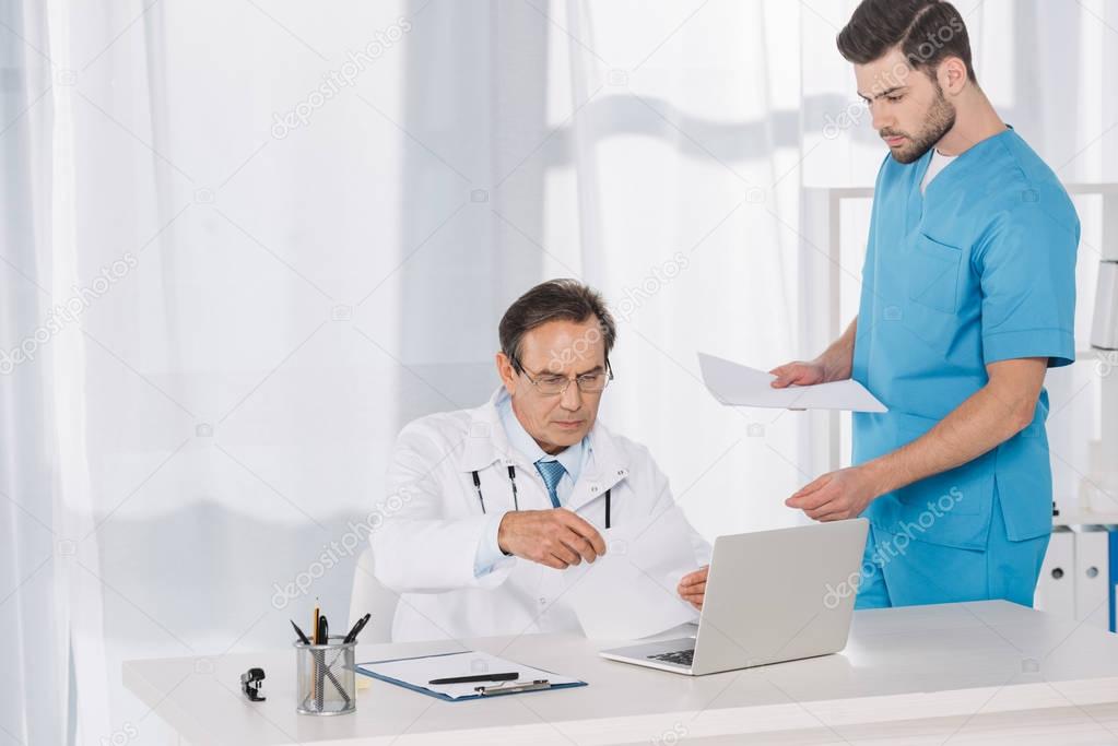 doctor reading documents and giving them to nurse