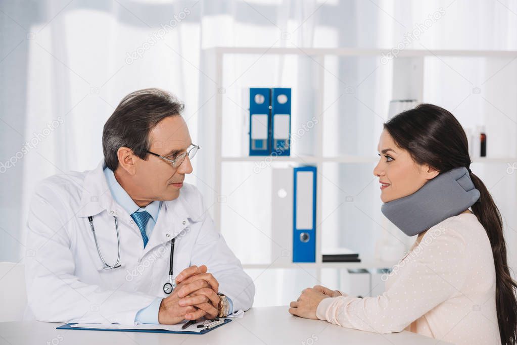 doctor sitting and talking with female patient in neck brace 