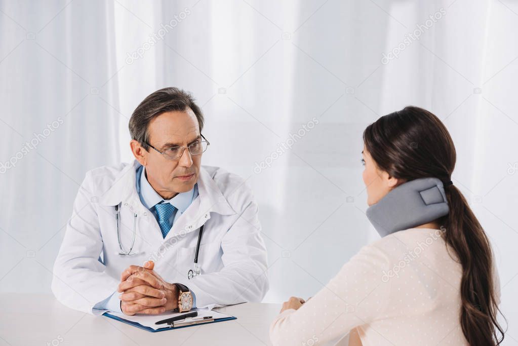 doctor sitting and talking with patient in neck brace 