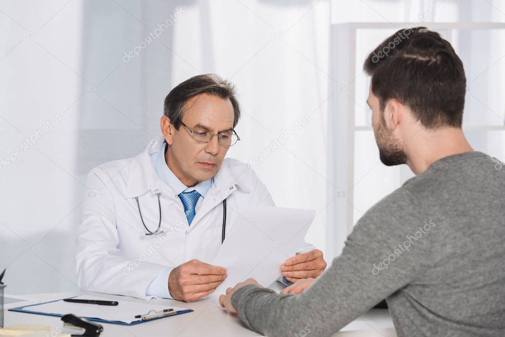 doctor reading male patient documents