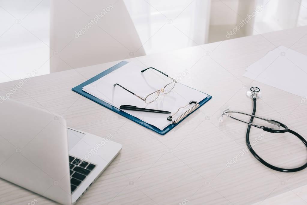 glasses and pen on clipboard on working table in hospital