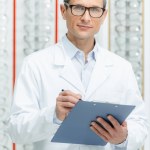 Portrait of optometrist with notepad in hands looking at camera in optics