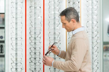 Beyaz adam optik gözlük çifti seçerek yan görünüm