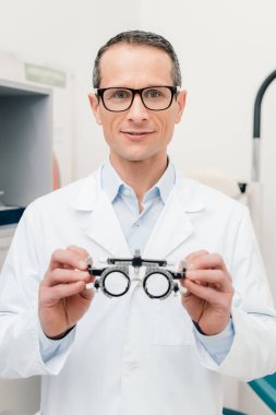 beyaz ceket deneme çerçeve klinik elinde tutan optometrist portresi