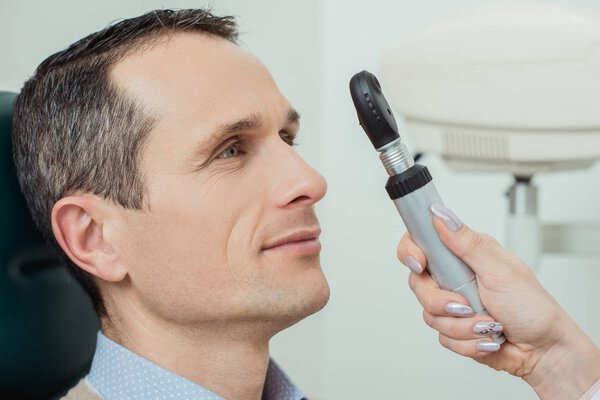 side view of man getting eye test by ophthalmologist in clinic