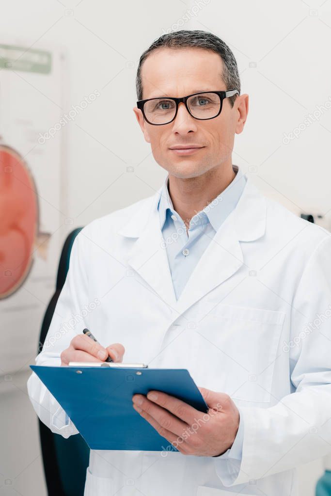 portrait of doctor with notepad in hands looking at camera in clinic