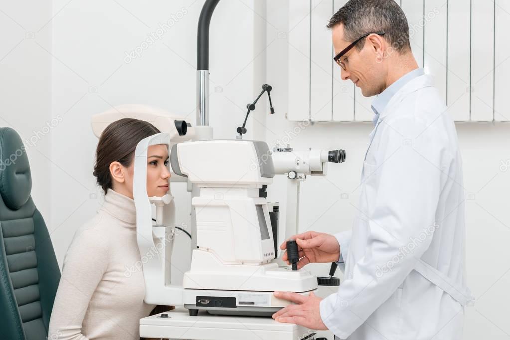 side view of young woman getting eye examination in slit lamp in clinic