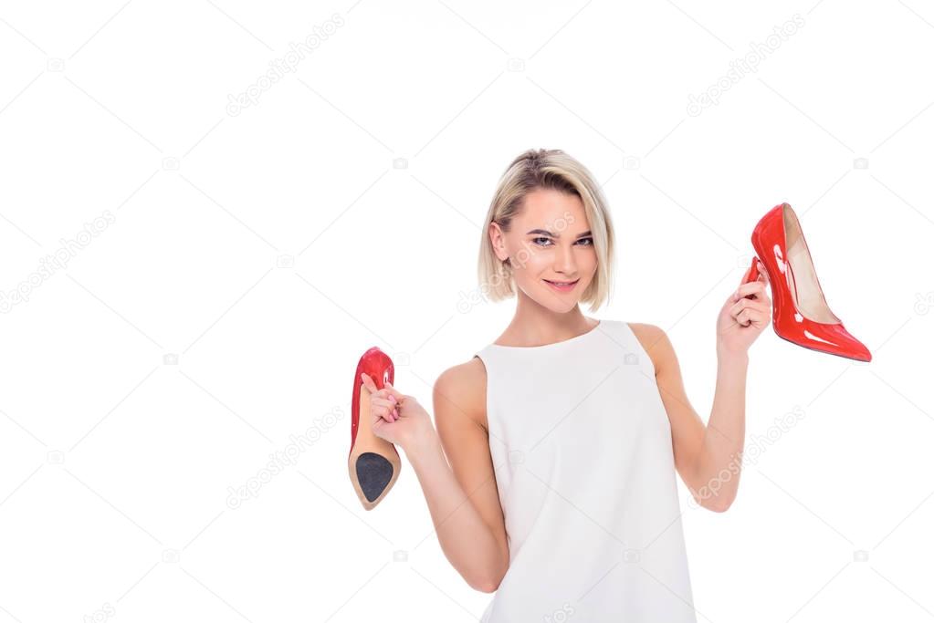 beautiful cheerful girl holding red heeled shoes, isolated on white