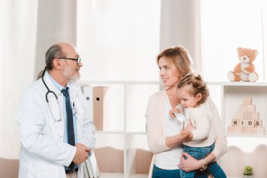 Anne küçük kız elindeki Kliniği ile gülümseyen kıdemli doktor portresi