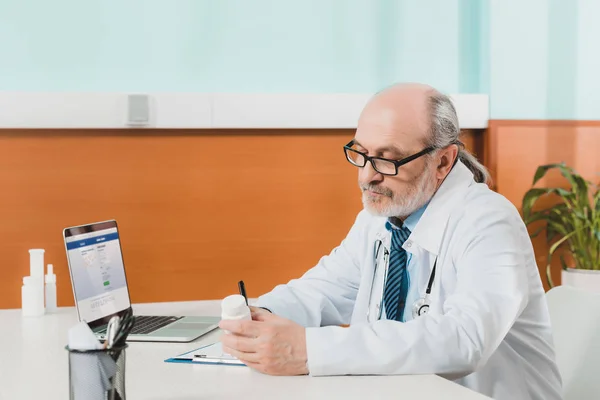 Side View Focused Senior Doctor Making Notes Notepad Workplace Laptop — Stock Photo, Image