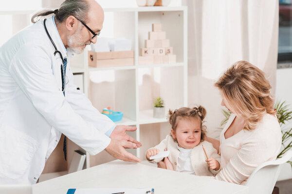 mother and crying  little daughter at doctors reception in clinic
