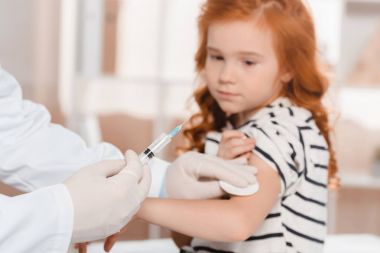 seçici odak bir doktor tıbbi eldiven Kliniği, küçük kız için enjeksiyon yapma