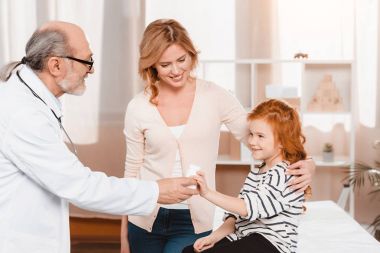 Doktor kliniğinde gülümseyen kız hap vererek yan görünüm