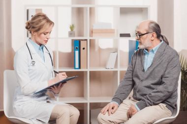 Doktor hasta şikayet Kliniği dinlerken Not Defteri ile beyaz ceket