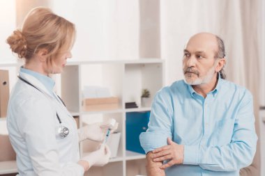 Klinik kıdemli hastada enjeksiyon yapmak için doktor Beyaz önlük going için