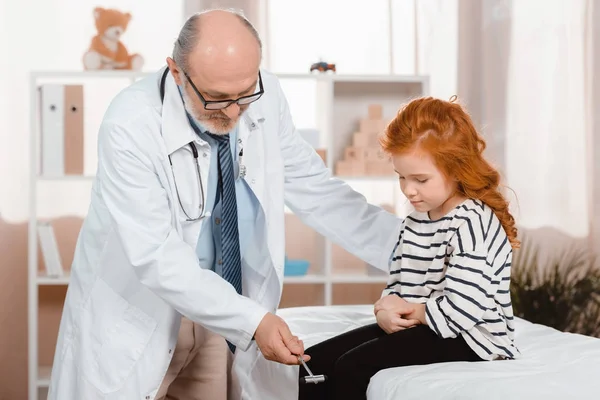 Pediatra Senior Bata Blanca Examinando Pequeño Paciente Con Martillo Reflejo — Foto de Stock