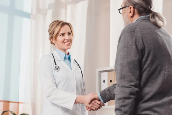 診療所で手を白衣で患者を振って笑顔医師の部分的なビュー — ストック写真