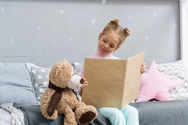 Очаровательный Маленький Ребенок Читает Книгу Постели Плюшевым Мишкой — стоковое фото