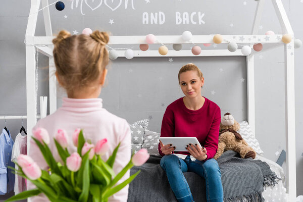 daughter hiding tulips bouquet for mother behind back