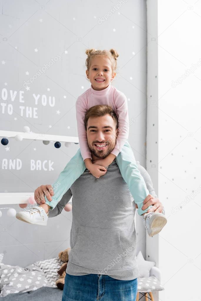 happy little daughter riding on father shoulders