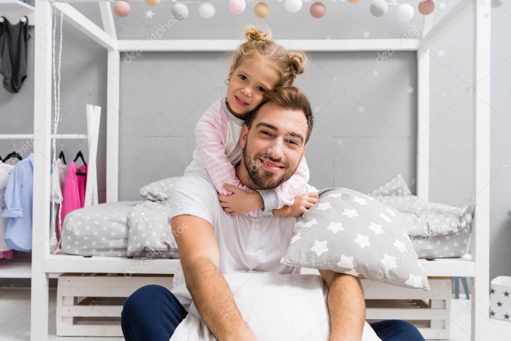 adorable daughter embracing father from behind in kid bedroom