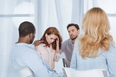 multiethnic middle aged people supporting depressed woman during anonymous group therapy clipart