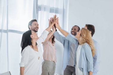 cheerful multiethnic mature people giving high five during group therapy clipart