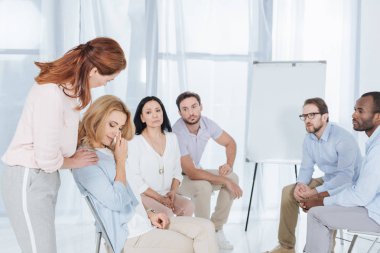 psychotherapist supporting middle aged woman during group therapy