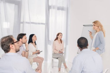 kadın psikoterapist boş beyaz tahta ve çok ırklı grup terapisi sırasında sandalyelere oturan işaret  