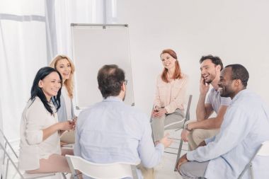 multiethnic middle aged people talking and smiling during group therapy clipart