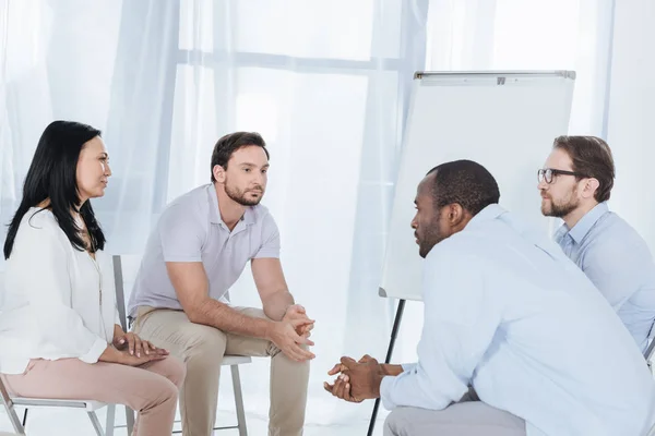 multiethnic middle aged people sitting on chairs during anonymous group therapy