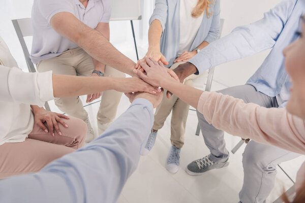 cropped shot of people stacking hands during group therapy