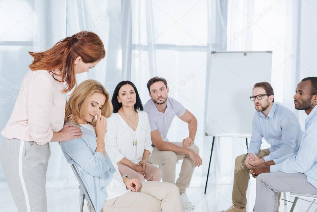 psychotherapist supporting middle aged woman during group therapy