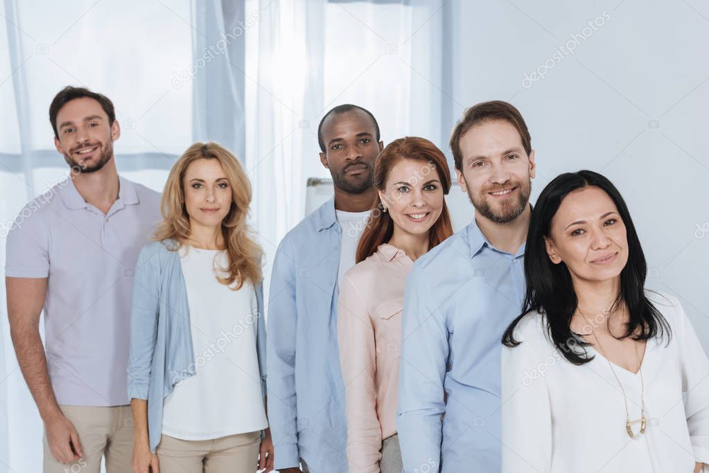 multiethnic mid adult people standing together and looking at camera