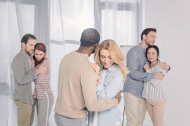 three multiethnic couples hugging during psychotherapy clipart