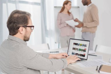 youtube Web sitesinde Office ekran ile dizüstü bilgisayar kullanarak gözlük içinde orta yaşlı adam