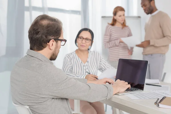 Mature Man Using Laptop Blank Screen While Multiethnic People Sitting — Stock Photo, Image