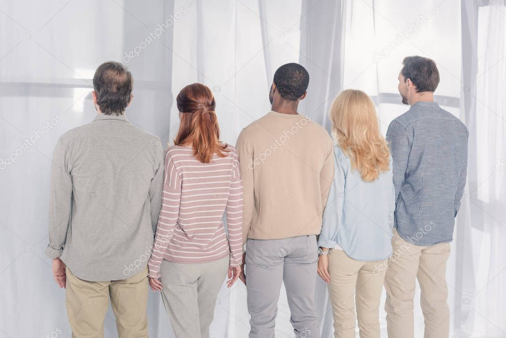 back view of multiethnic people standing together during group therapy 